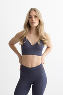 Woman wearing a dark gray sports bra and leggings set on a white background