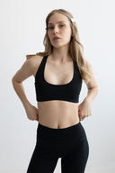Woman wearing a black sports bra and leggings on a white background