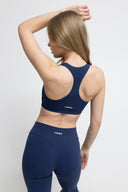 Woman wearing a navy sports bra and leggings with 'Marvelous' branding on a white background