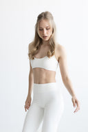 Woman wearing a white athletic outfit with black sneakers on a white background