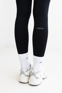 Black leggings with 'metime' logo worn by a person on a white background