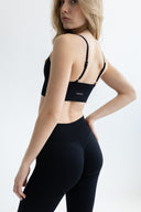 Woman wearing a black sports bra and leggings on a white background