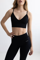 Woman wearing a black sports bra and leggings on a white background
