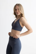 Woman wearing a dark blue sports bra and leggings on a white background