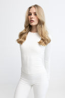 Woman wearing a white outfit against a plain background